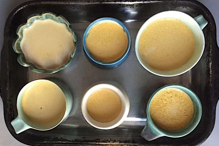 Unbaked Pumpkin Pudding in Cups and Bowls in a water bath ready to go into the oven